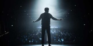 Silhouette of a speaker on stage with an audience in the background